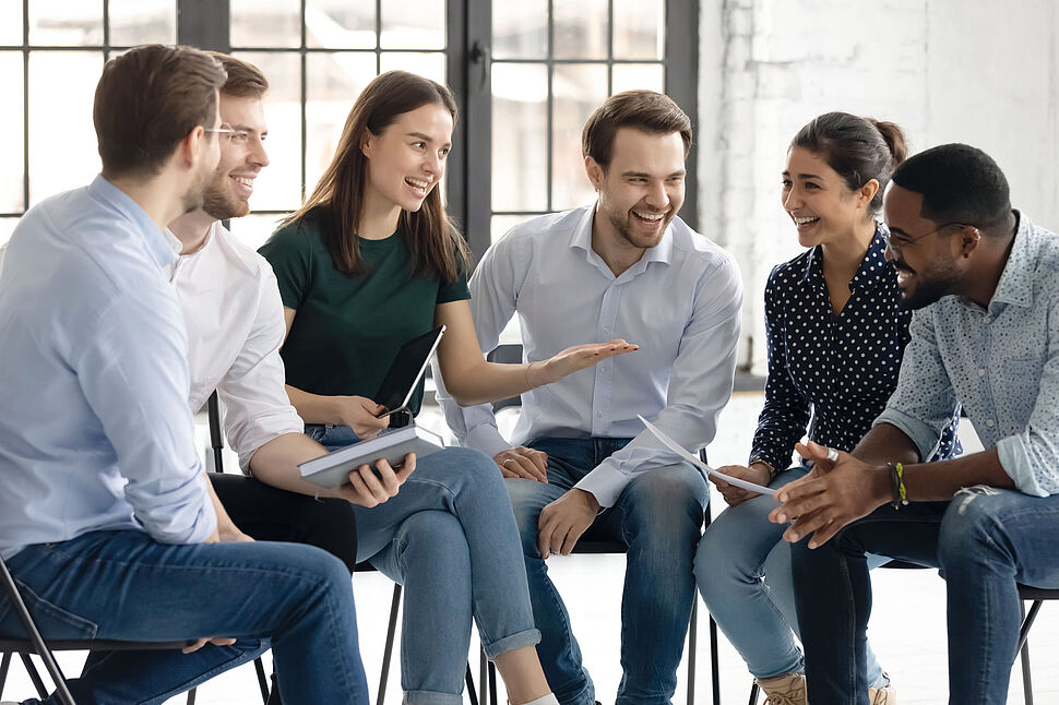 Inhouse-Schulungen Eine Gruppe Menschen sitzt in einem Stuhlkreis und unterhalten sich