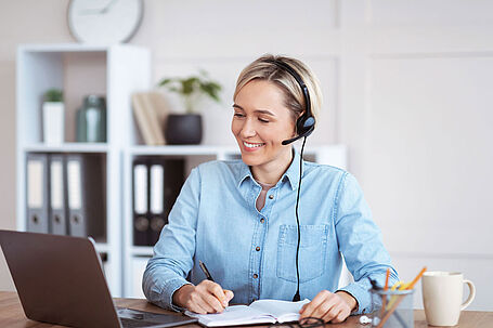 Eine Frau mit Headset am Schreibtisch